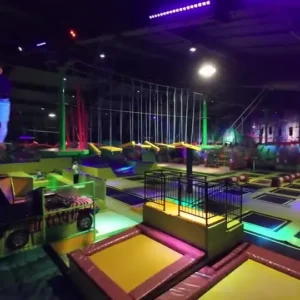 Neonowo oświetlona hala Jungle Park Pruszków z trampolinami i torem przeszkód
